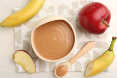 Photo of Delicious baby food in bowl and ingredients on white wooden table, flat lay