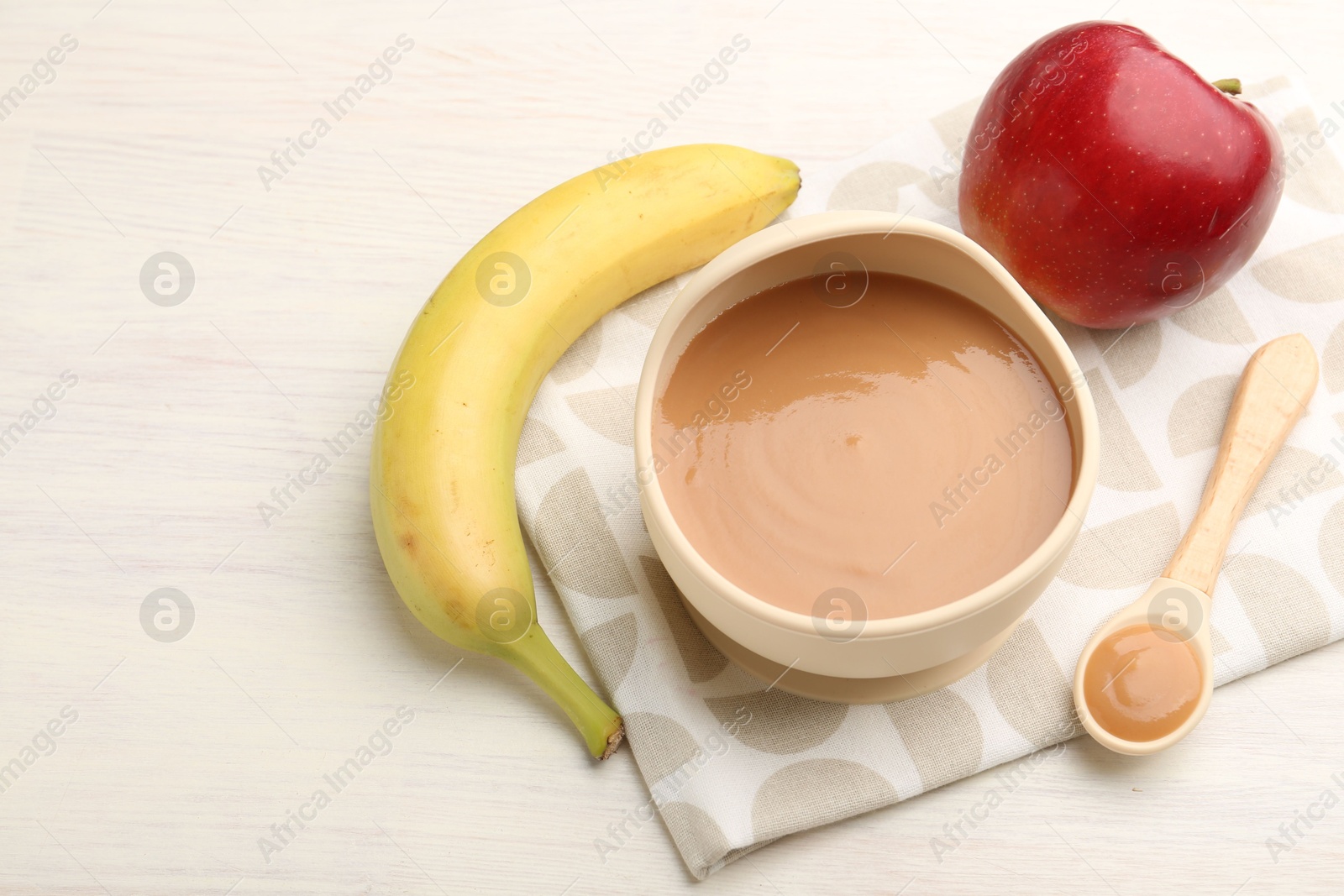 Photo of Delicious baby food in bowl and ingredients on white wooden table