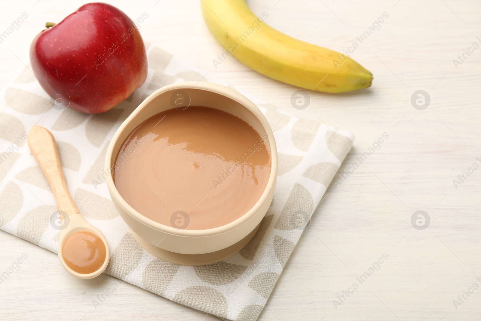 Photo of Delicious baby food in bowl and ingredients on white wooden table