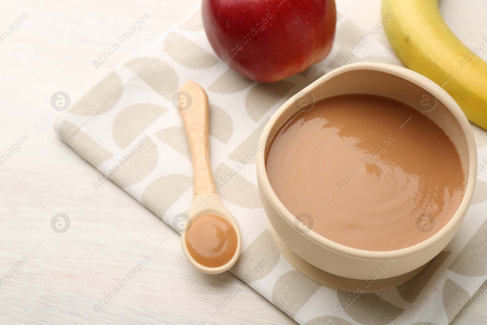 Photo of Delicious baby food in bowl and ingredients on white wooden table