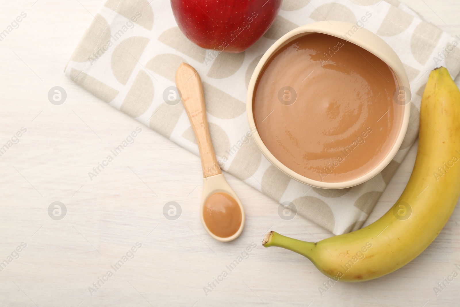 Photo of Delicious baby food in bowl and ingredients on white wooden table, flat lay