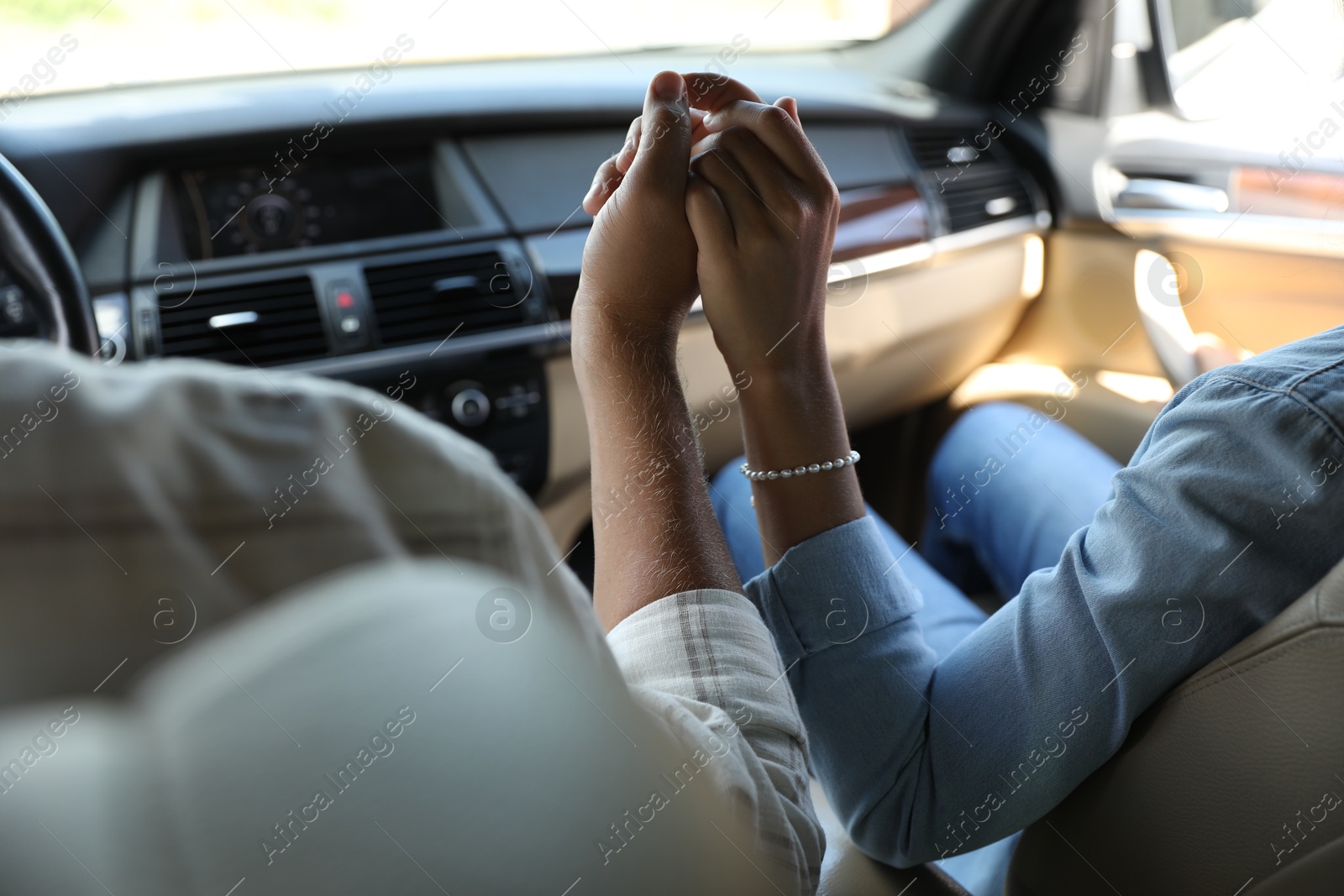 Photo of Lovely couple holding hands together while traveling by car, closeup