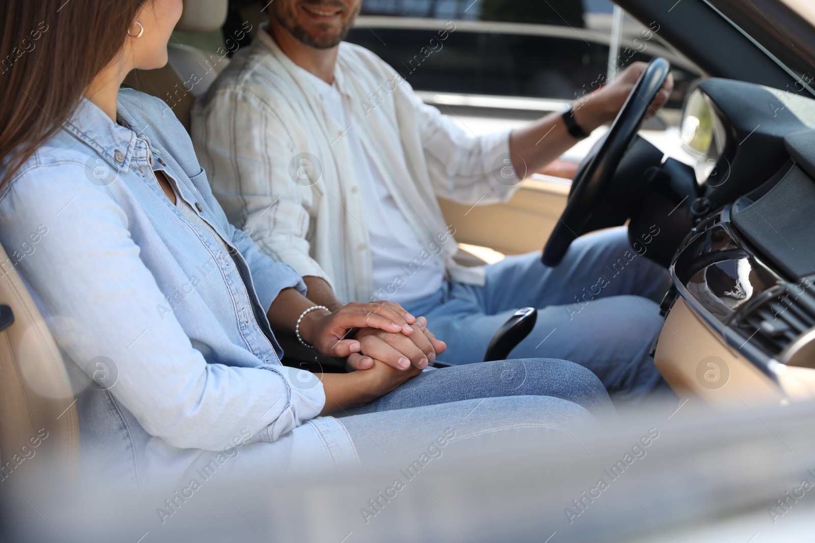 Photo of Lovely couple holding hands together while traveling by car, closeup