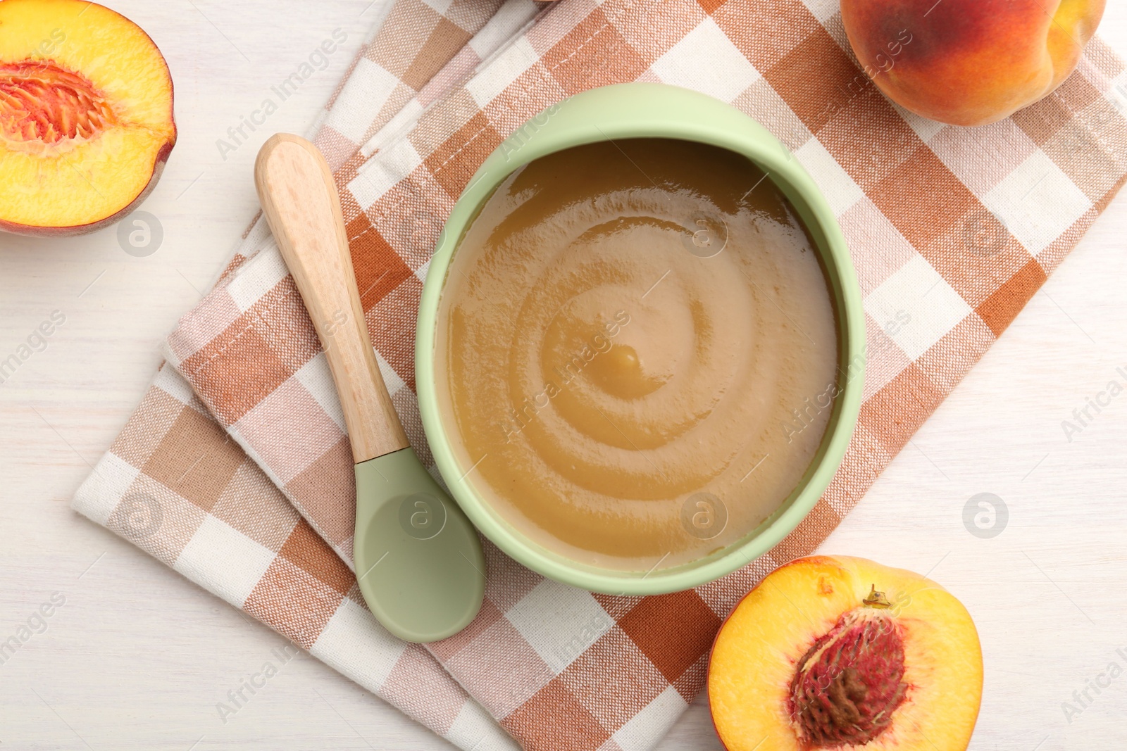 Photo of Delicious baby food in bowl and fresh ingredients on white wooden table, flat lay