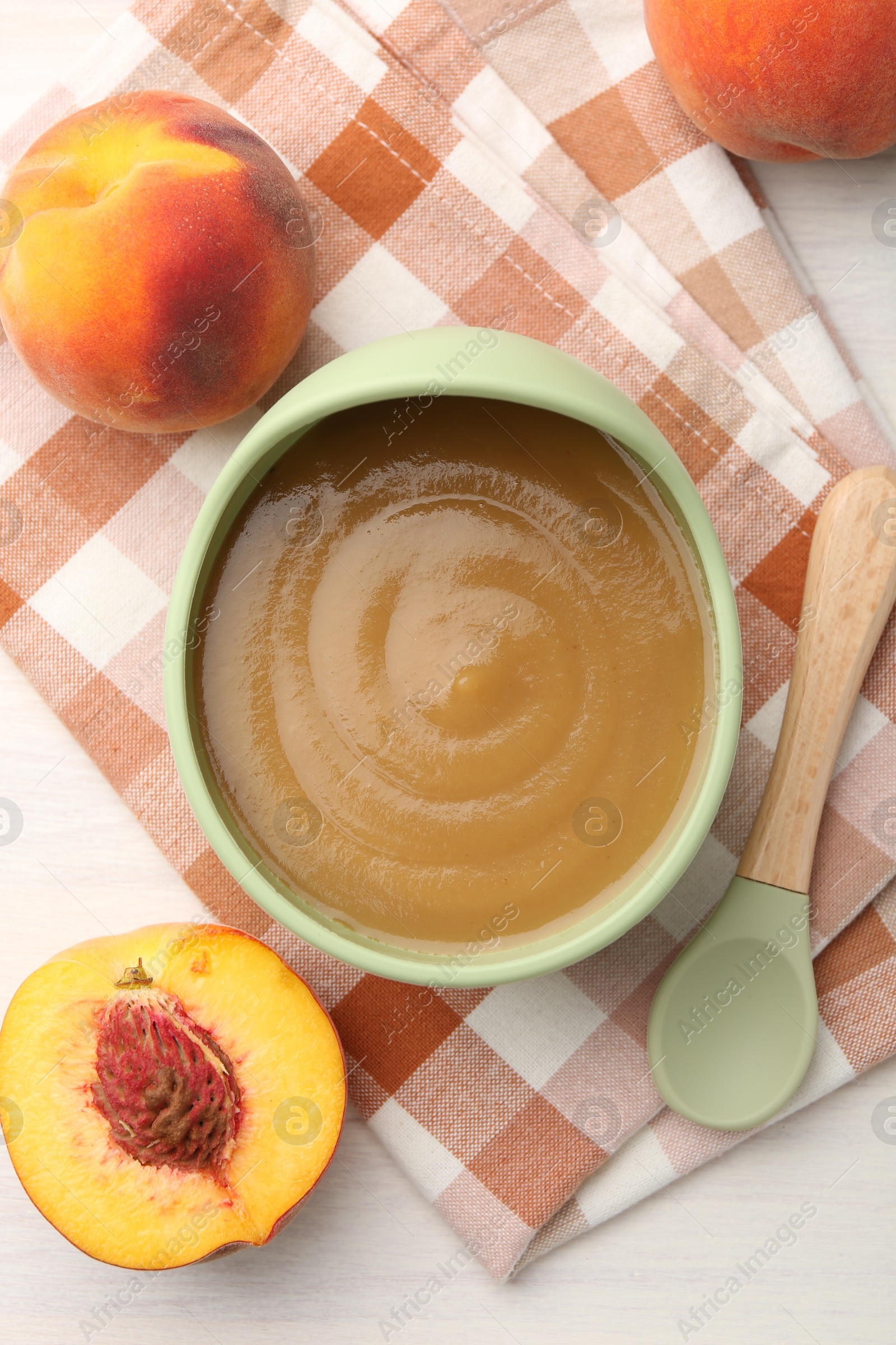 Photo of Delicious baby food in bowl and fresh ingredients on white wooden table, flat lay