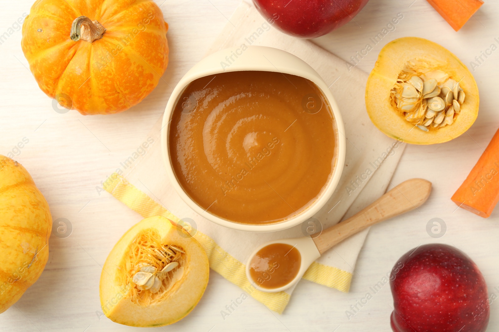 Photo of Delicious baby food in bowl and fresh ingredients on white wooden table, flat lay