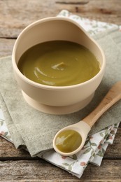 Photo of Delicious baby food in bowl with spoon on wooden table