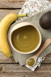 Photo of Delicious baby food in bowl with spoon and fresh ingredients on wooden table, flat lay