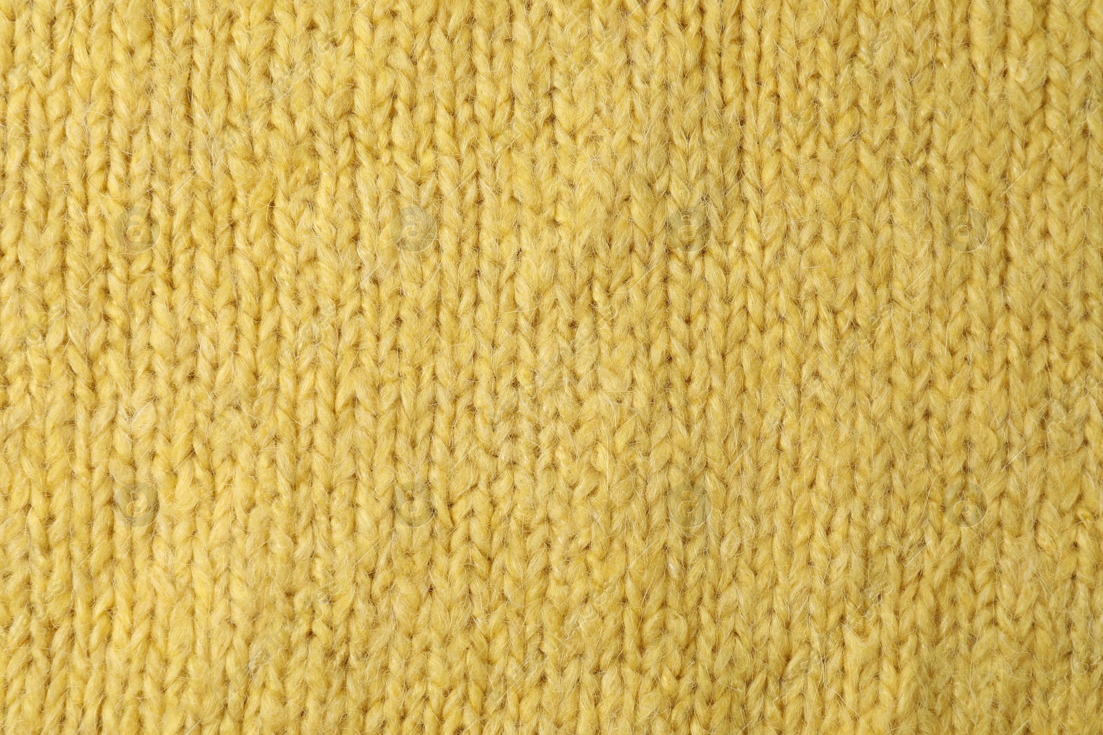 Photo of Texture of yellow knitted fabric as background, top view