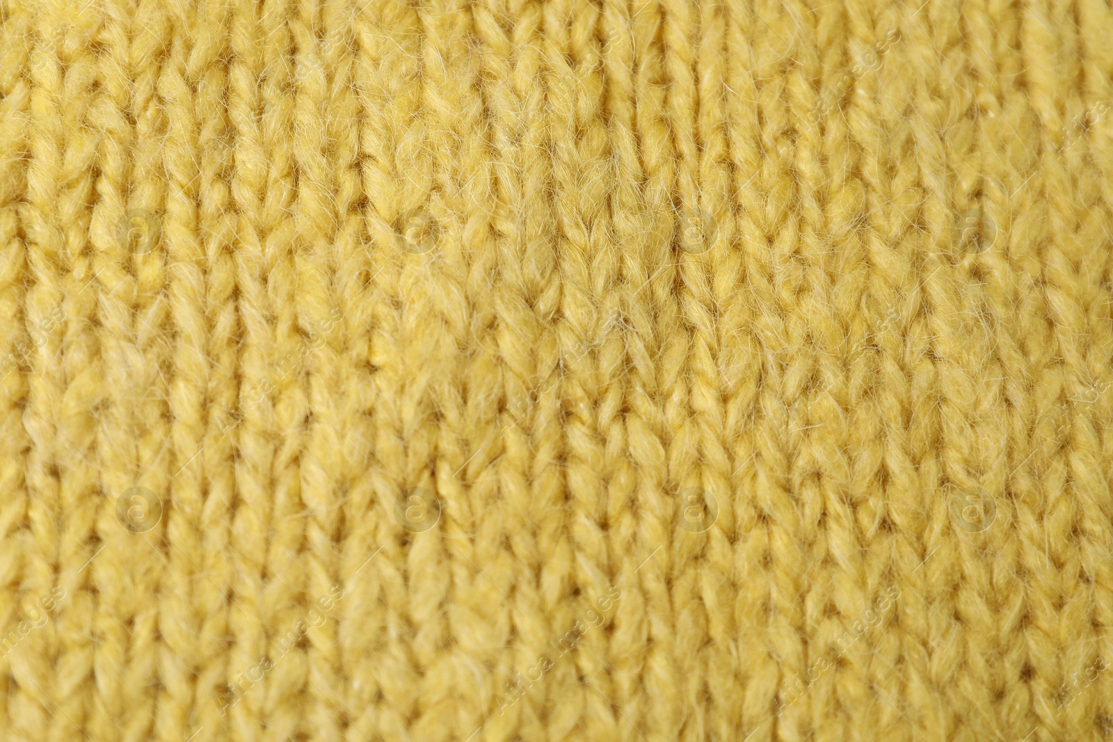 Photo of Texture of yellow knitted fabric as background, top view