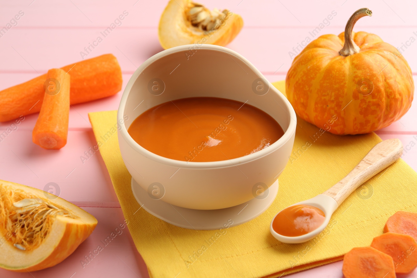 Photo of Delicious baby food in bowl and fresh ingredients on pink wooden table