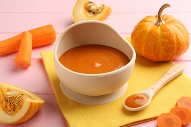 Photo of Delicious baby food in bowl and fresh ingredients on pink wooden table