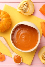 Photo of Delicious baby food in bowl and fresh ingredients on pink wooden table, flat lay