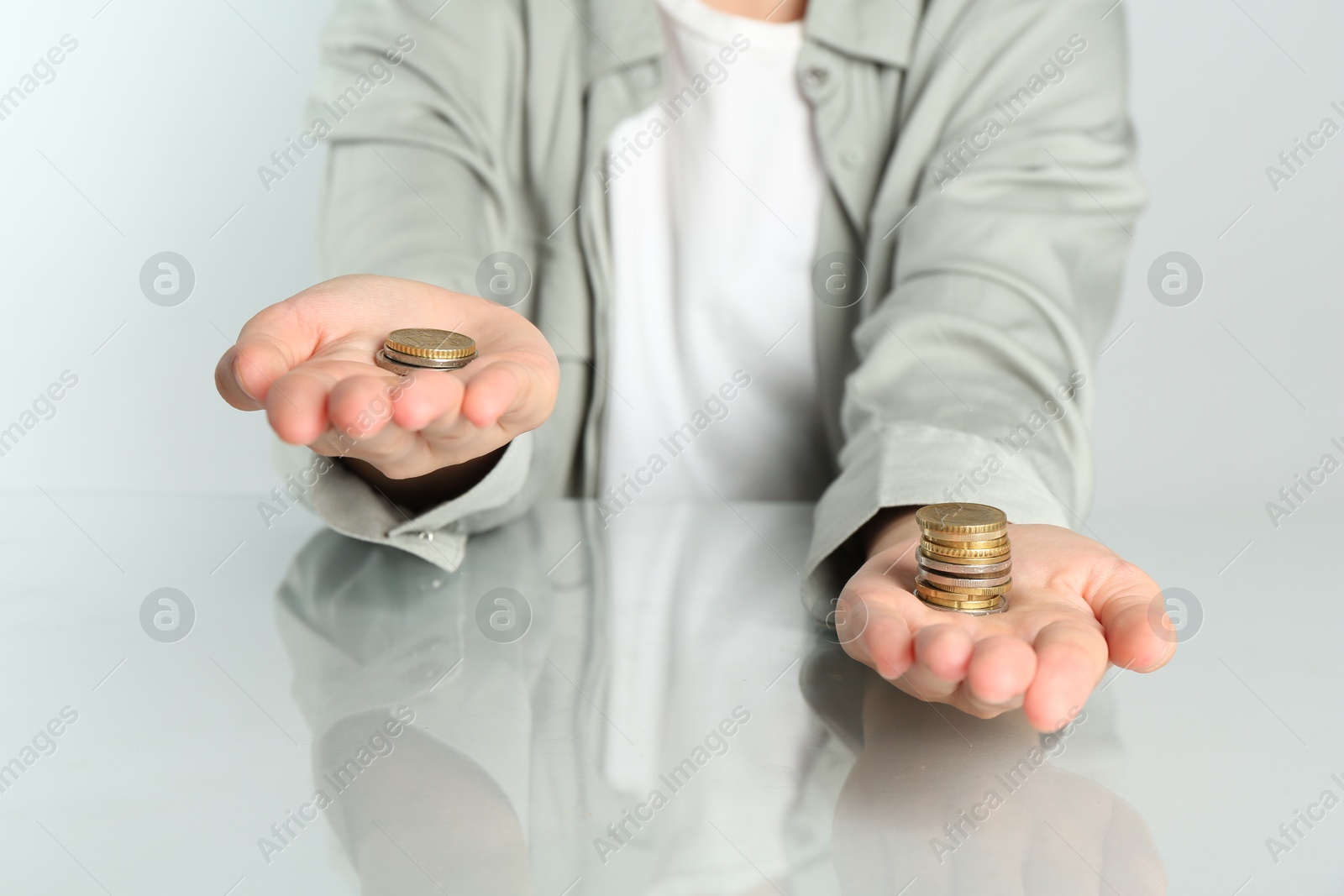 Photo of Financial inequality. Woman comparing two stacks of coins at table, closeup