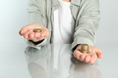 Photo of Financial inequality. Woman comparing two stacks of coins at table, closeup