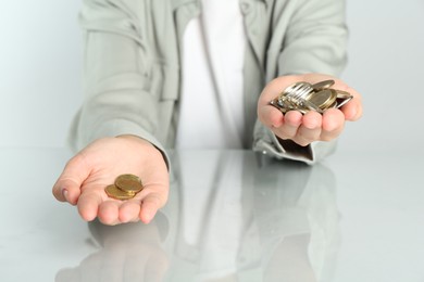 Photo of Financial inequality. Woman comparing coins in hands at white table, closeup