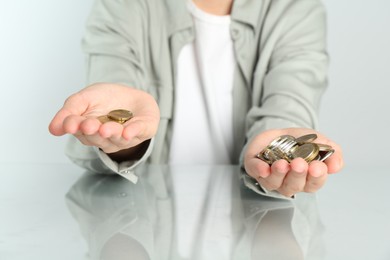 Photo of Financial inequality. Woman comparing coins in hands at white table, closeup