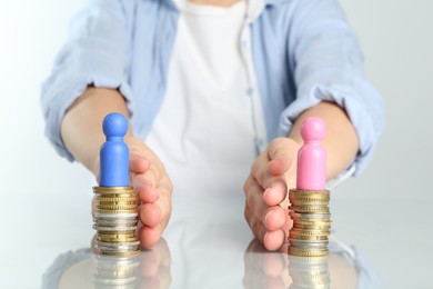 Financial equality. Woman moving stacks of coins with male and female figures away from each other at table, closeup