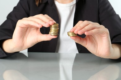 Photo of Financial inequality. Woman comparing two stacks of coins at table, closeup