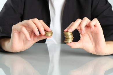 Photo of Financial inequality. Woman comparing two stacks of coins at table, closeup