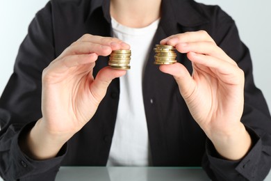 Financial equality. Woman comparing two stacks of coins at table, closeup