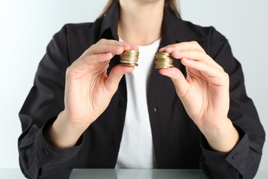 Financial equality. Woman comparing two stacks of coins at table, closeup