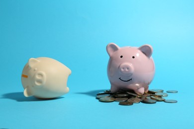 Financial inequality. Piggy bank with coins and empty one on light blue background