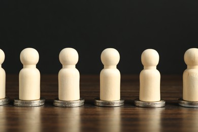 Photo of Financial equality. Wooden figures with similar quantity of coins on table