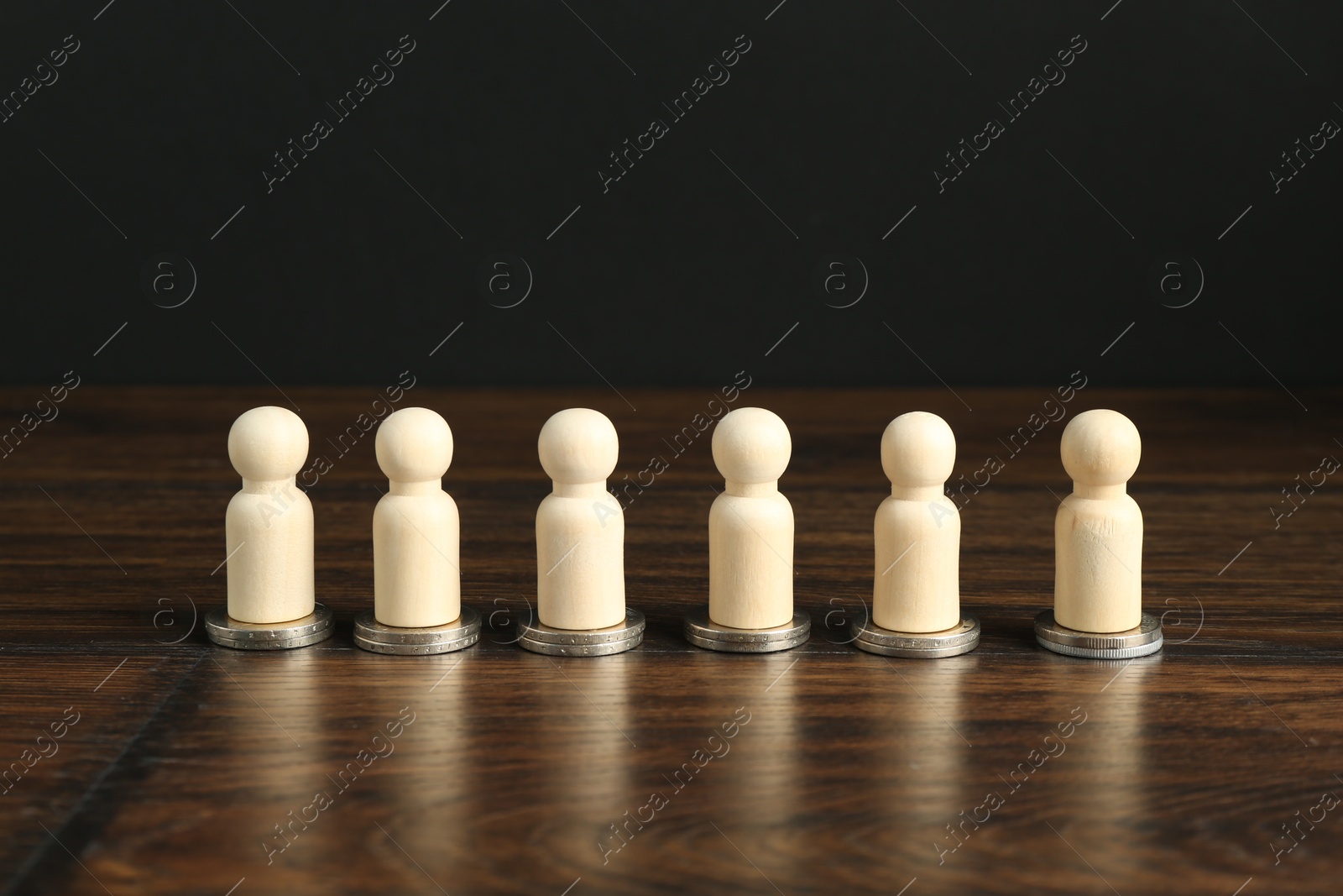 Photo of Financial equality. Wooden figures with similar quantity of coins on table. Space for text