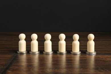 Photo of Financial equality. Wooden figures with similar quantity of coins on table. Space for text