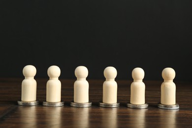 Photo of Financial equality. Wooden figures with similar quantity of coins on table. Space for text