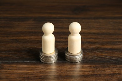 Photo of Financial equality. Wooden figures with similar quantity of coins on table