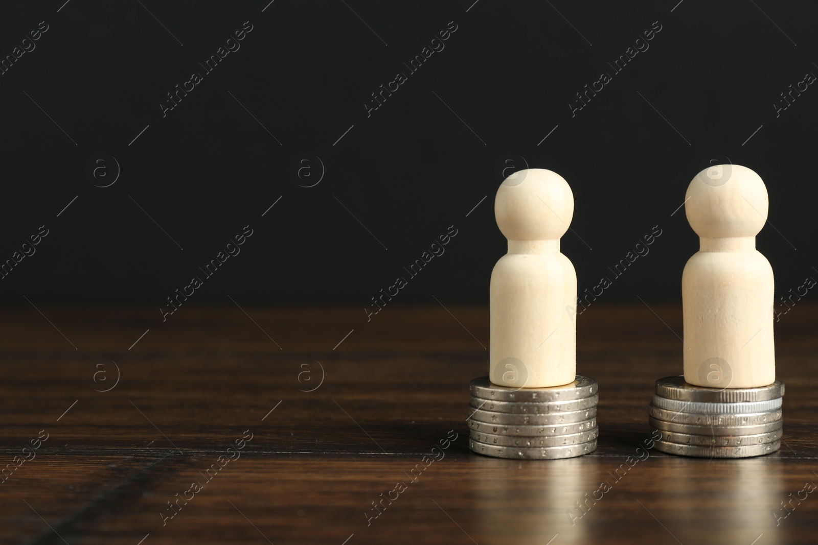 Photo of Financial equality. Wooden figures with similar quantity of coins on table. Space for text