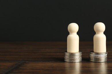 Photo of Financial equality. Wooden figures with similar quantity of coins on table. Space for text