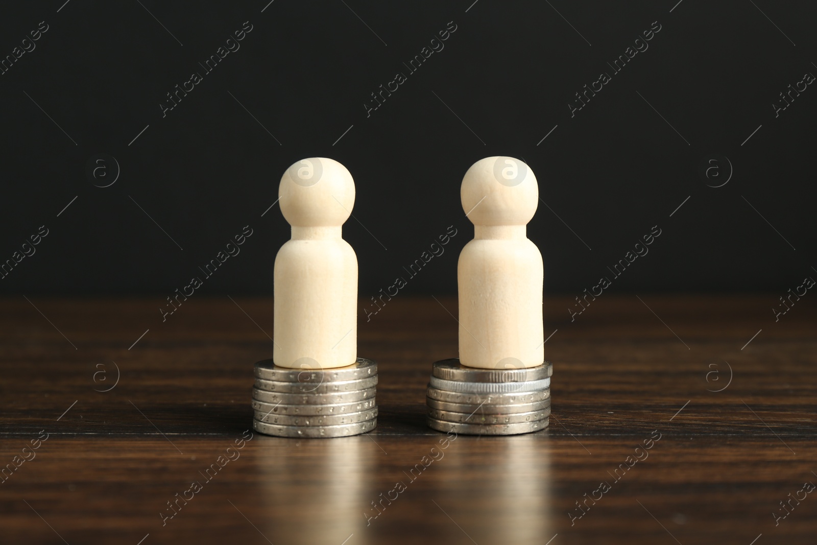 Photo of Financial equality. Wooden figures with similar quantity of coins on table