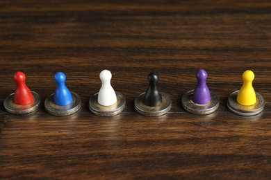 Photo of Financial equality. Colorful game pieces with similar quantity of coins on wooden table