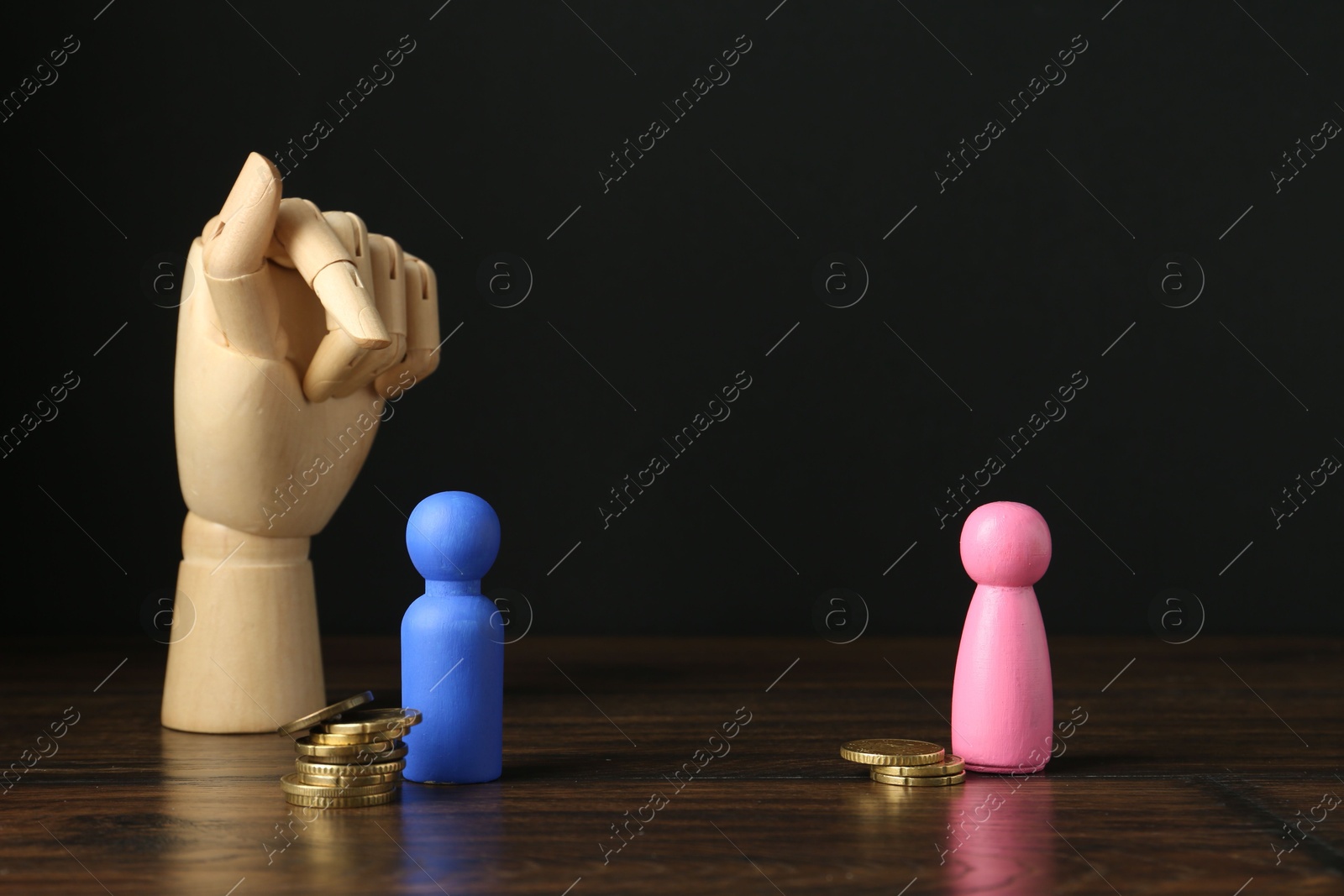 Photo of Financial inequality. Male and female figures with uneven amount of coins and mannequin hand on wooden table