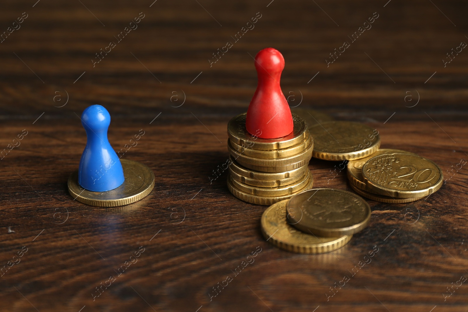 Photo of Financial inequality. Male and female figures with uneven amount of coins on wooden table