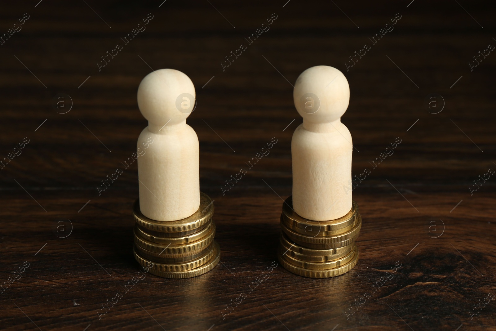 Photo of Financial equality. Wooden figures with similar quantity of coins on table