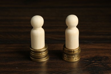 Photo of Financial equality. Wooden figures with similar quantity of coins on table