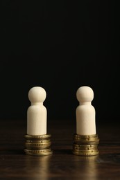 Photo of Financial equality. Wooden figures with similar quantity of coins on table