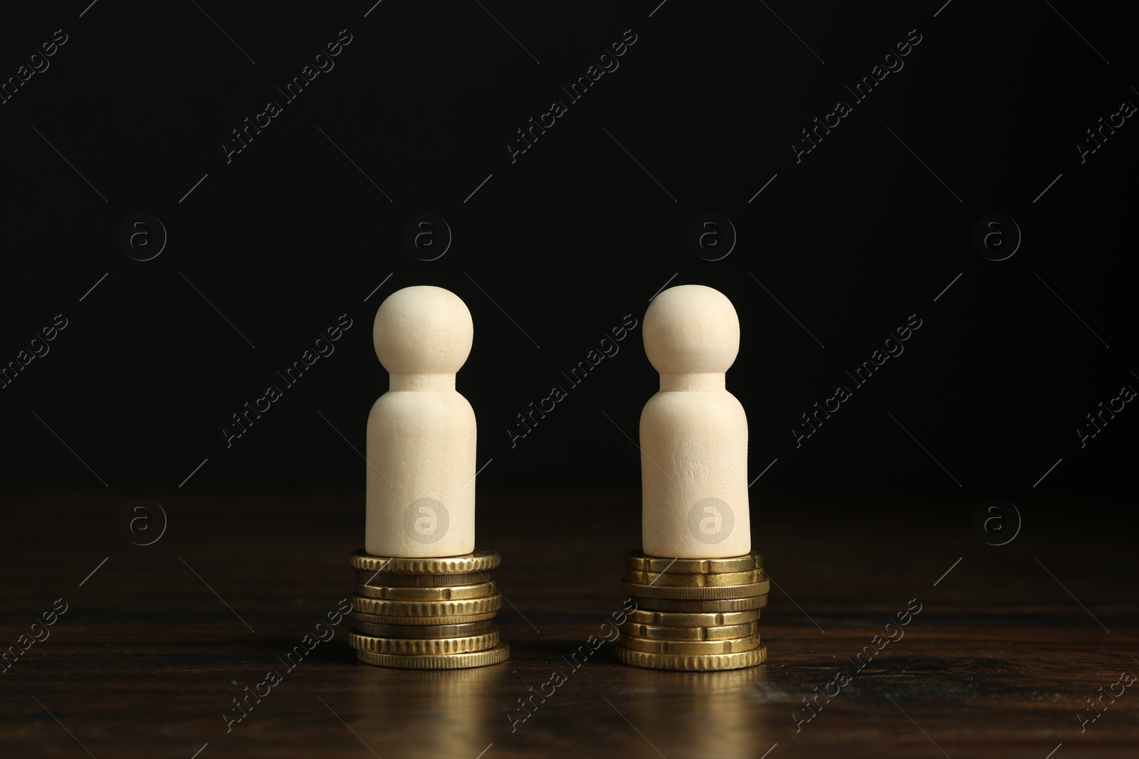 Photo of Financial equality. Wooden figures with similar quantity of coins on table