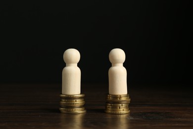 Financial equality. Wooden figures with similar quantity of coins on table