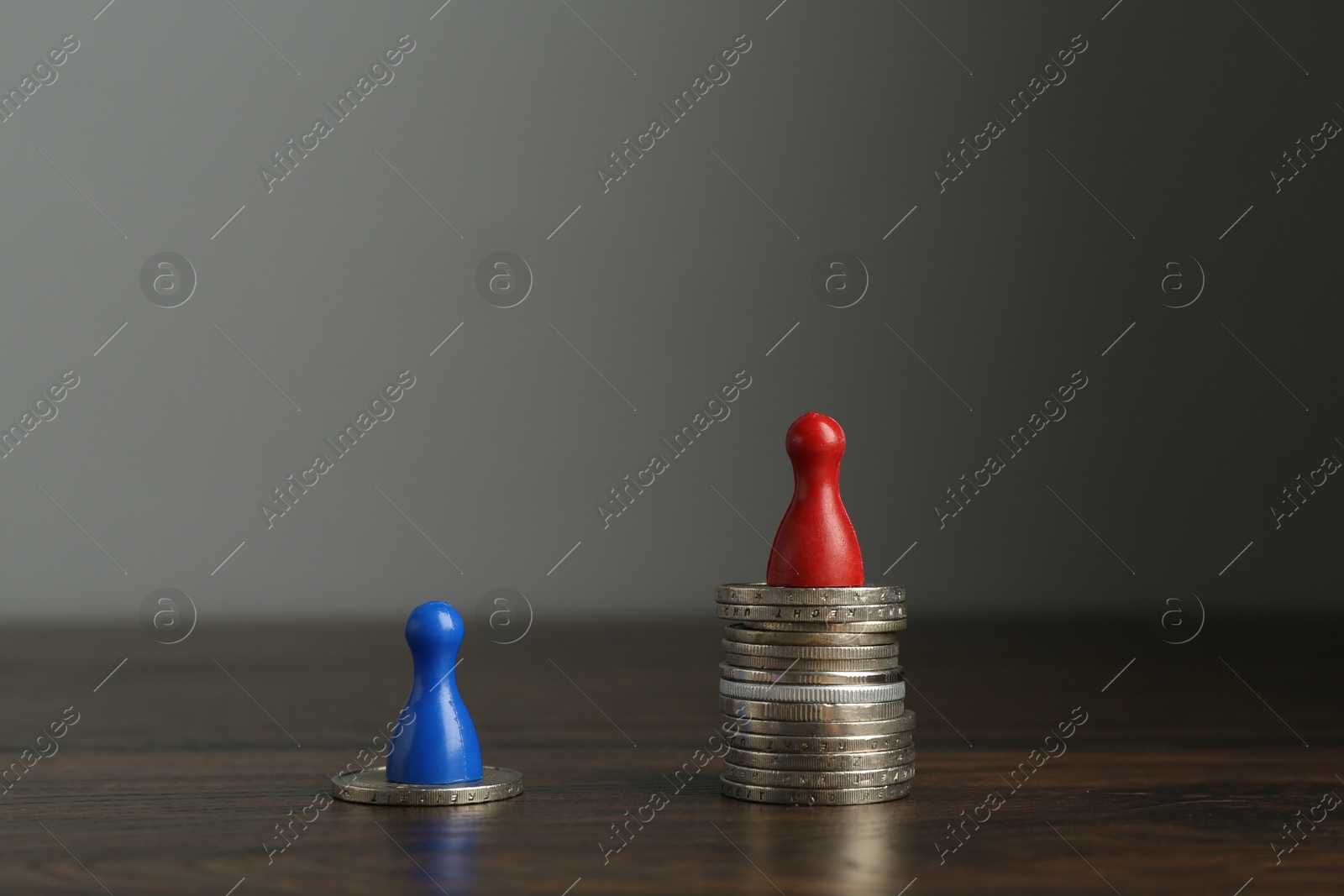 Photo of Financial inequality. Male and female figures with uneven amount of coins on wooden table