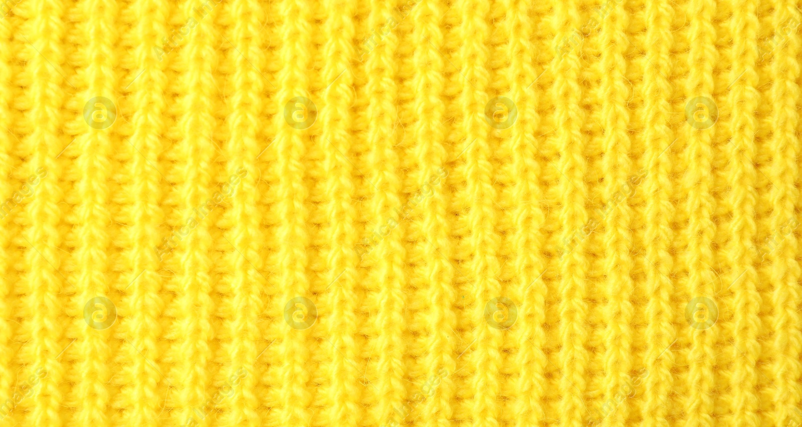 Photo of Texture of yellow knitted fabric as background, top view