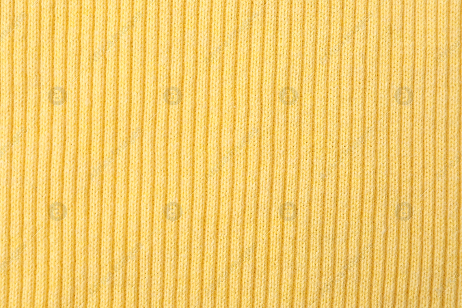 Photo of Texture of light yellow knitted fabric as background, top view