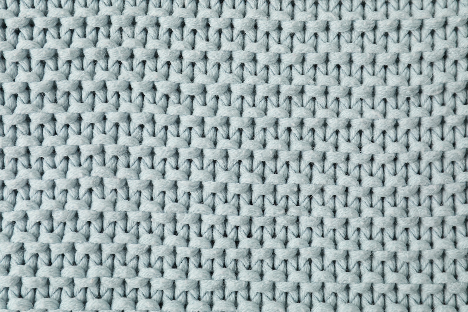 Photo of Texture of light blue knitted fabric as background, top view