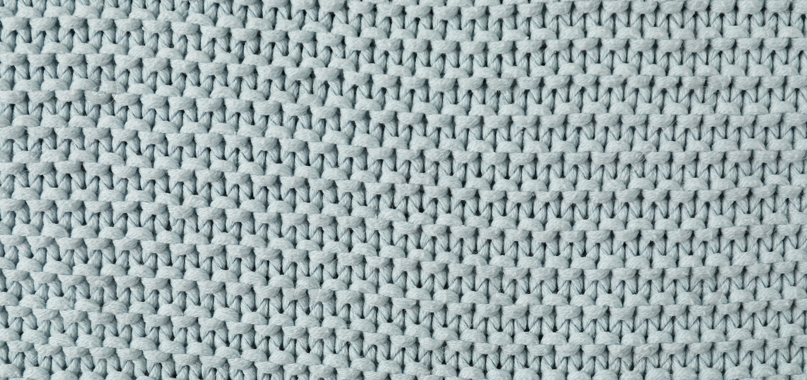 Photo of Texture of light blue knitted fabric as background, top view