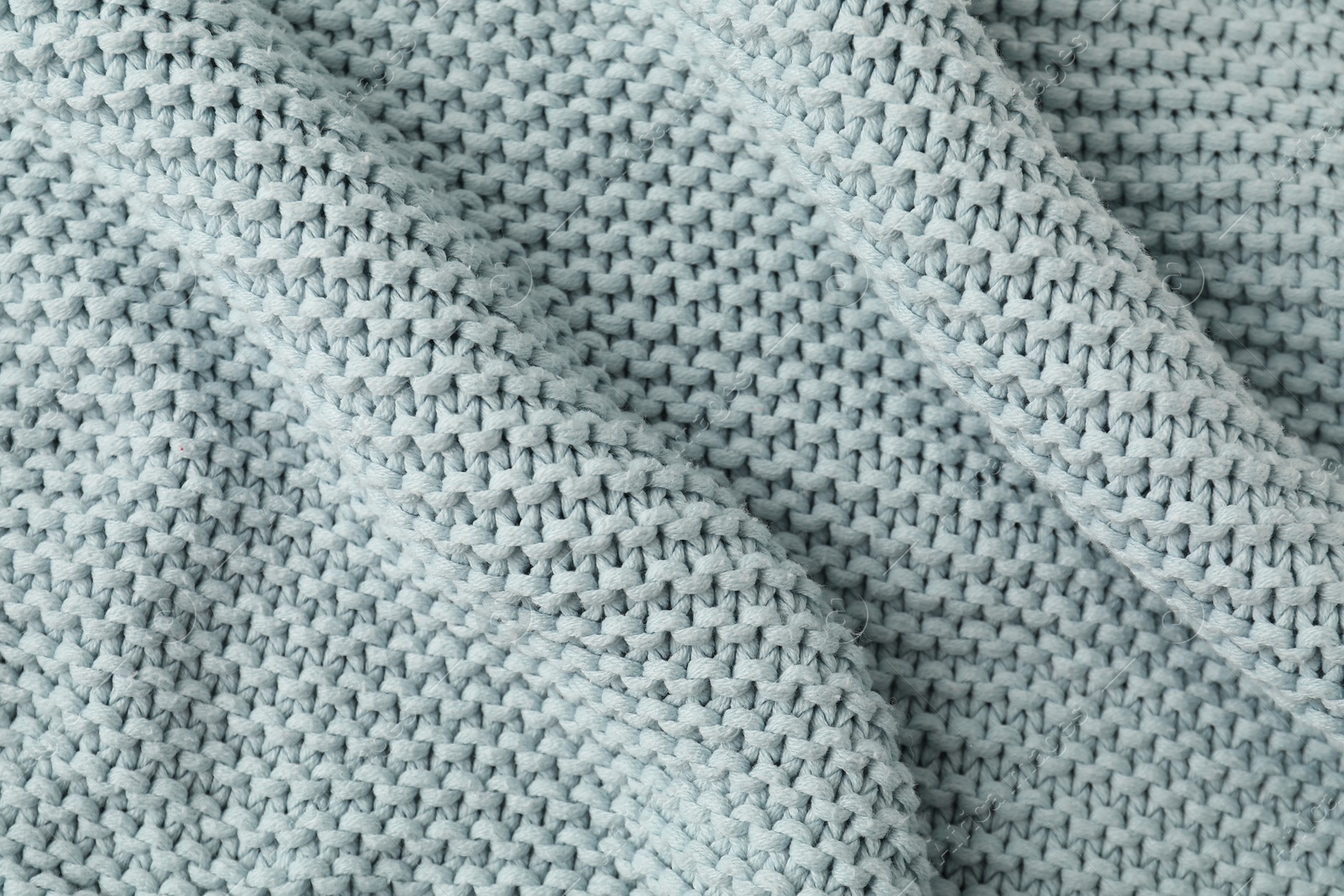 Photo of Texture of light blue knitted fabric as background, top view