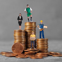 People of various professions on stacks of coins of different height against grey background